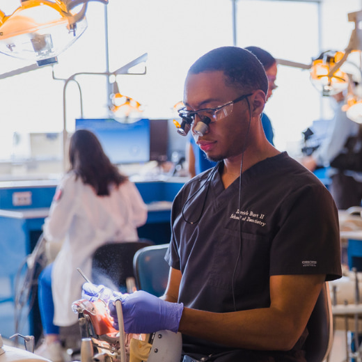 A dental student examines his work in a lab.